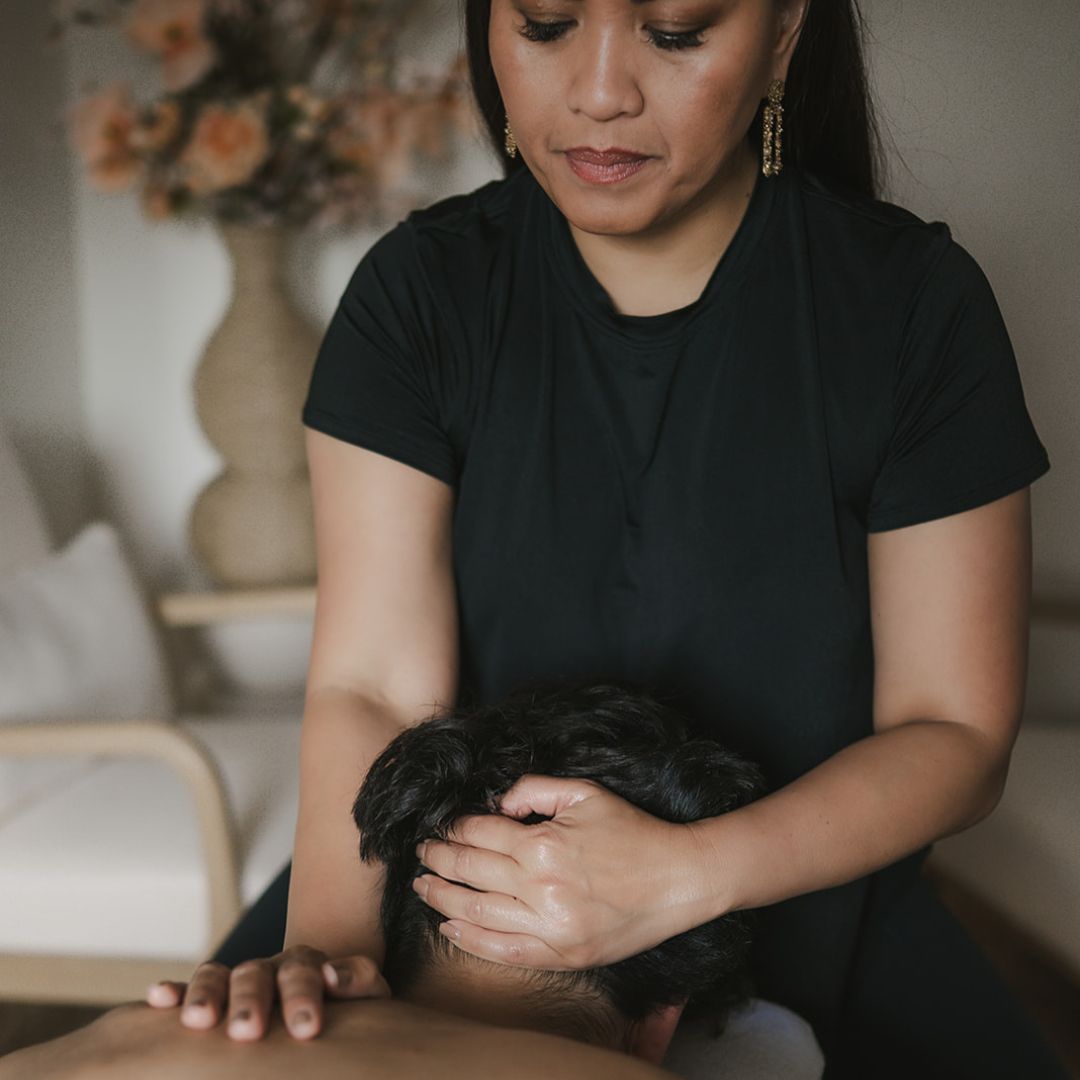 Vrouw in zwarte top houdt een masseert de rug van een man, met zachte blik en ontspannen houding.